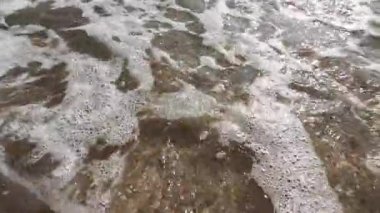 Dalgalar yavaşça kumlu sahilde süzülüyor