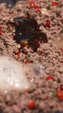 Yer bifteği, mutfak ortamında biber ve sosla kızartılır. Yakın çekim aşçılık sürecini vurgular