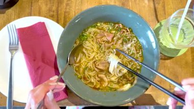 Bir insan Bangkok 'ta yemek çubuklarıyla Vietnam piposunun tadını çıkarıyor. Parlak ışıklandırma yemeğin canlı renklerini vurgular