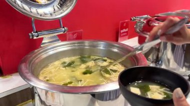 Bangkok 'taki Kore BBQ restoranında bir kişi açık büfeden miso çorbası servis ediyor.