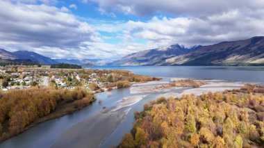 Havadan çekilen görüntüler Glenorchy 'nin dinamik gökyüzü altında akan nehir, renkli ağaçlar ve görkemli dağlarla dolu canlı sonbahar manzarasını yakalar.