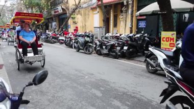Turistler kalabalık Hanoi caddesinde bisiklet sürmekten zevk alıyorlar