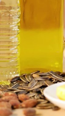 Ahşap zemin üzerinde yağ şişeleri olan ayçiçeği ve badem tohumlarının yakın plan çekimleri, doku ve renkleri vurguluyor