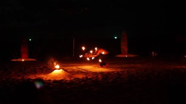 Karon Sahili, Phuket 'te büyüleyici bir yangın gösterisi. Yetenekli hokkabazlıklar ve parlak alevler karanlık, kumlu bir arka plana karşı.