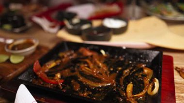 Sıcak bir restoran ortamında, sıcak tortilla ve soslarla çevrili, biberli ve soğanlı sığır eti fajitaları.