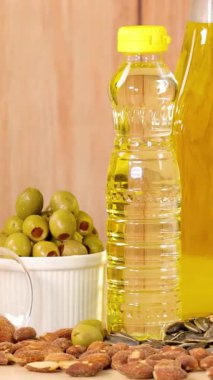 Ahşap bir arka planda yağlar, fındıklar, avokadolar ve tereyağı gibi sağlıklı yağların yakın plan görüntüsü.