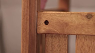 Eller, yumuşak ışıklandırılmış bir ortamda mobilya montajı için ahşap parçaları dikkatlice hizalayarak, işçiliğin ve detaylara dikkat etmenin altını çiziyor