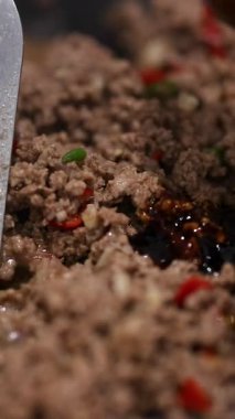 Sos ile pişirilen sığır kızartmasının yakın çekimi, canlı malzemelerin altını çizmek ve mutfak ortamında dinamik karışım