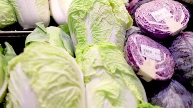 Bir süpermarket ortamında parlak ışık altında taze marul ve kırmızı lahana. Tazelik ve canlı renkleri vurguluyorlar.