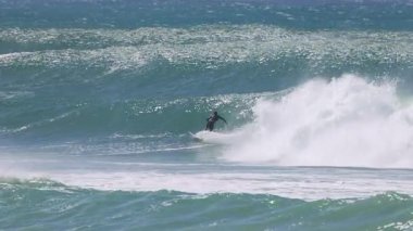 Sörfçü Kirra Sahili 'nde dalgalara biniyor.