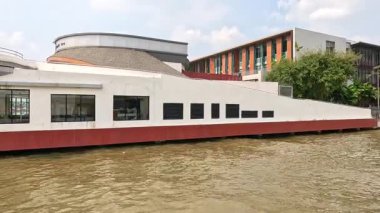 Bangkok 'ta nehir kıyısında dairesel mimarisi olan modern bir bina. Durgun suyla gün ışığında ele geçirildi.