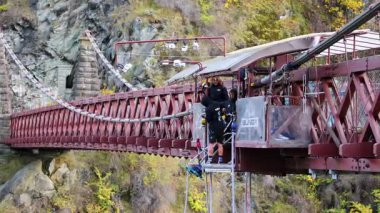 Queenstown, Yeni Zelanda 'daki manzaralı bir köprüden bungee jumping, dinamik hareketlerle canlı gün ışığında yakalandı.