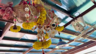 Canlı çiçek ve yelpaze süslemeleri Tayland 'ın Phuket kentindeki bir tepedeki restoranın güneşli çatısının altında asılı.