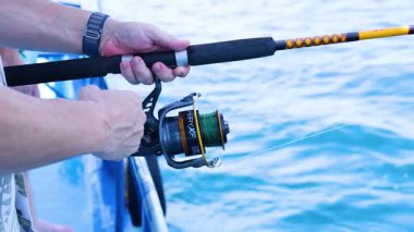 Tayland, Phuket 'te bir teknede ustalıkla olta manevrası yapıyorlar. Parlak gün ışığı dingin okyanus arkaplanını vurgular