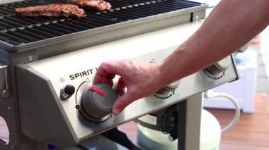 Bir el, gaz ızgarasının düğmelerini ayarlar ve ısı seviyelerini kontrol eder. Parlak ışıklandırma paslanmaz çelik yüzeyi ve pişirme alanını vurgular