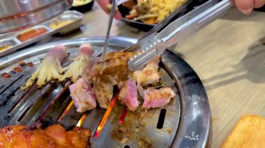 Kore barbekü et ızgarasının Bangkok 'taki bir masa üstü ızgarasında canlı renkleri ve dinamik pişirme hareketlerini vurguluyor.