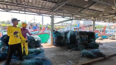 Bir balıkçı deniz kenarında balık ağları organize eder..