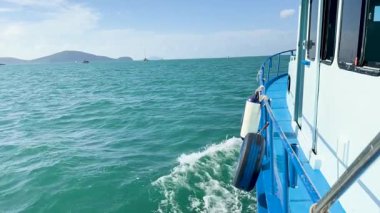 Tayland, Phuket yakınlarındaki turkuaz sularda yüzen bir tekne, yeniden kullanılmış bir lastiği çamurluk olarak kullanıyor. Parlak gün ışığı dingin okyanus manzarasını güçlendirir.