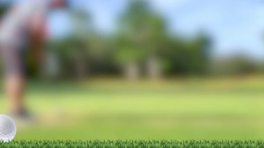 Bir golf topu dinamik bir şekilde yeşil bir pistte hareket eder ve arka planda bulanık bir golfçü vardır.