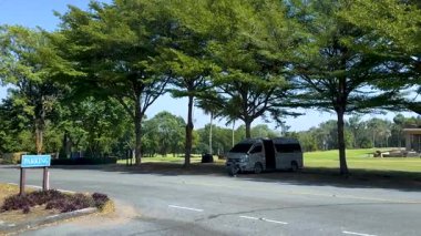 Golf kulübündeki ağaçların altında duran minibüs.