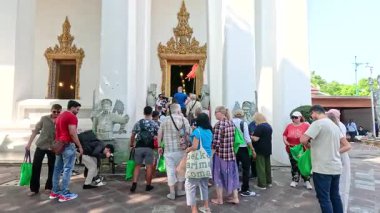 Bir grup turist Bangkok 'taki Wat Pho Tapınağı' nın girişinde toplanarak canlı atmosferi ve kültürel keşifleri yakaladılar.