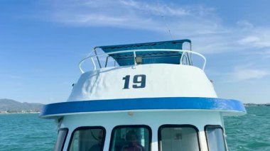 Bir tekne Chalong Körfezi 'nde süzülüyor, sakin okyanus manzarasını ve açık gökyüzünün altındaki uzak tepeleri yakalıyor.