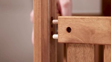 Eller, yumuşak ışıklandırılmış bir ortamda ahşap mobilyalar monte ediyor. Yakından bakıldığında hassasiyet ve işçilik vurgulanıyor
