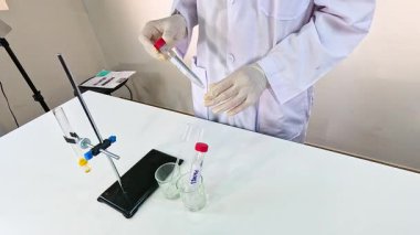 Bilim adamı bir laboratuvar ortamında kimyasal reaksiyonlar ve renk değişiklikleri gösteren bir bromol mavi deneyi yürütüyor.