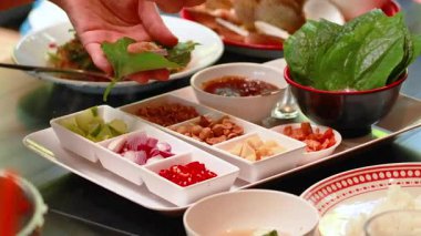 Eller, Phuket, Tayland 'daki bir masada taze malzemelerle Miang Kham' ı bir araya getiriyor. Parlak ışıklandırma canlı renkleri ve dokuları vurgular