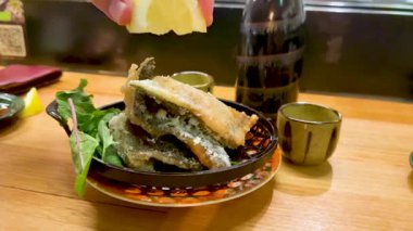 Limon ve yeşillikle servis edilen kızarmış balık.