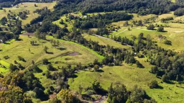 Nimbin, NSW 'nin canlı yeşil manzaralarını ve yuvarlanan tepelerini gün ışığı altında gösteren hava görüntüleri.