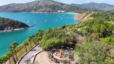 Tayland, Phuket 'teki Nai Harn Sahili' nin canlı sahil şeridini ve yemyeşil yeşilliğini gün ışığında gösteren hava görüntüleri.