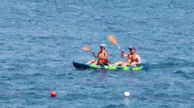 İki kişi okyanusta kayak yapıyor.