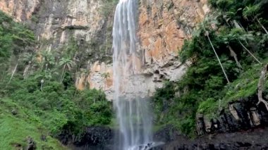 Şelale kayalık bir uçurumdan aşağı yuvarlanıyor.