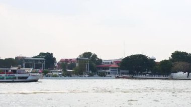 Tekneler Chao Phraya Nehri 'ni, Bangkok' un mimarisinin bir zeminine karşı yumuşak gün ışığında geçerek kentsel ve kültürel dinamikleri yakalıyor.