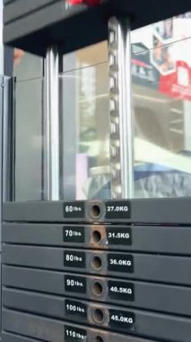 Spor salonundaki güverte makinesinde ağırlık yığını hareketinin yakın plan görüntüsü, egzersiz sürecini vurgular