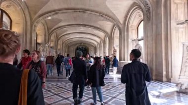 İnsanlar büyük bir müze koridorunda yürüyor.