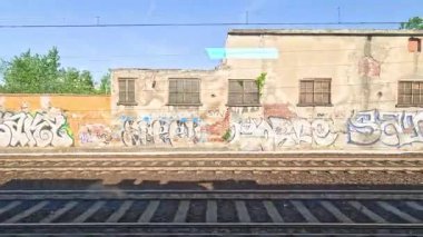 Grafiti kaplı duvarlar hareket halindeki bir trenden görünüyor.