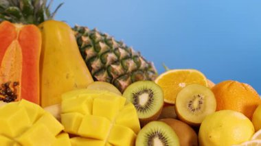 Mavi arka planda sıralanmış çeşitli meyveler