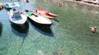 Tekneler yanaştı, insanlar berrak sularda yüzüyor.