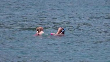 Bir baba ve kız, berrak sularda şnorkelle yüzmekten, maske takmaktan ve parlak güneş ışığı altında okyanusu keşfetmekten hoşlanırlar.