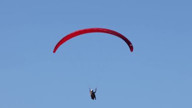 Paraglider açık mavi gökyüzünde süzülüyor