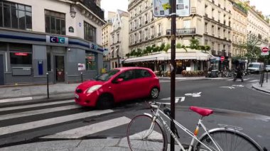 Kırmızı araba işlek bir şehir kavşağından geçiyor..