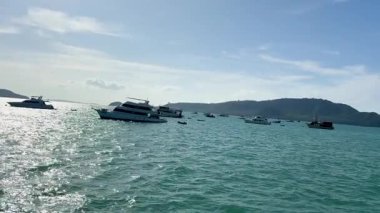 Phuket 'in Chalong Körfezi' nde sakin bir tekne yolculuğu, berrak gökyüzü altında canlı okyanus manzaraları ve balıkçılık aktiviteleri yakalamak.