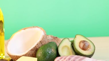 Parlak yeşil zemine karşı hindistan cevizi ve avokado içeren çeşitli yağlar. Parlak ışıklandırmalı statik bileşim