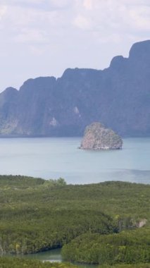 Phang Nga Körfezi 'nin sakin panoramik manzarası yemyeşil, kireçtaşı kayalıkları ve yumuşak gün ışığı altında sakin suları.