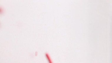 Kırmızı kalp şeklindeki şekerler ve serpintiler beyaz bir yüzeye dökülür ve canlı, tatlı bir kompozisyon oluşturur.