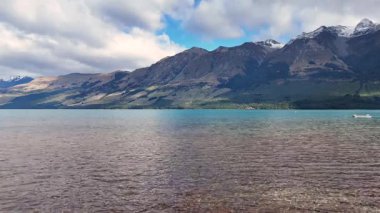 Glenorchy, Yeni Zelanda 'da dağlı sakin bir göl manzarası. Açık gökyüzü ve sakin sular huzurlu bir atmosfer yaratır.