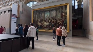 İnsanlar Paris müzesinde büyük bir tabloyu inceliyor.