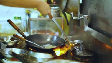 Aşçı ustalıkla mutfakta tavayla yemek pişiriyor.